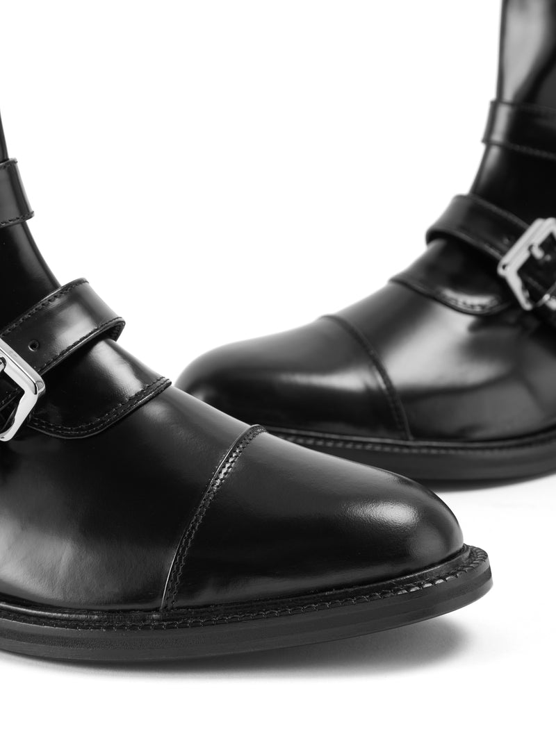 Close up picture of CWEN ankle glossed leather black boots, with two straps, two silver buckles, light tan colour lining and a leather sole
