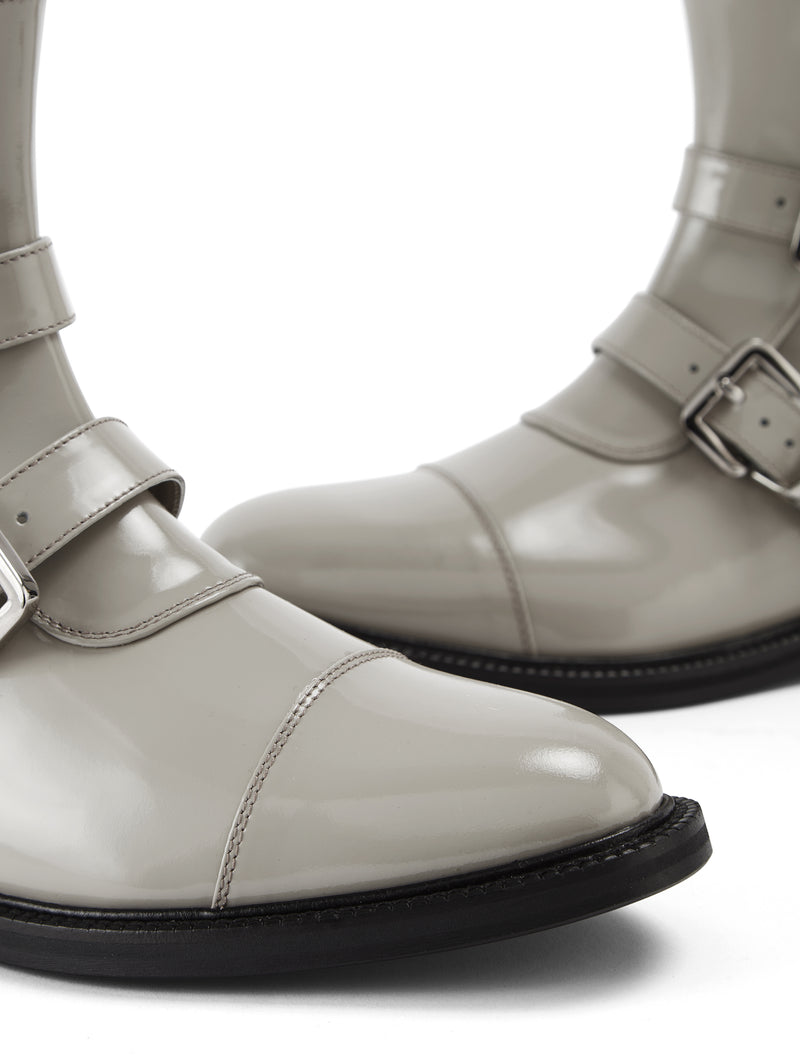 Close up picture of CWEN ankle glossed light grey leather boots, with two straps, two silver buckles, light tan colour lining and a leather sole