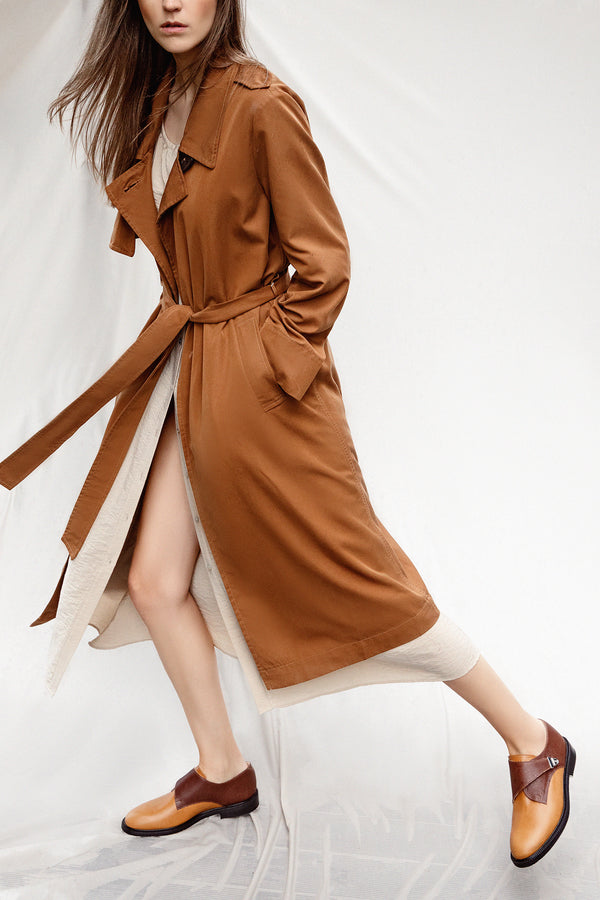 Woman in terracotta colour trench coat wearing tan colour leather CWEN monk shoes