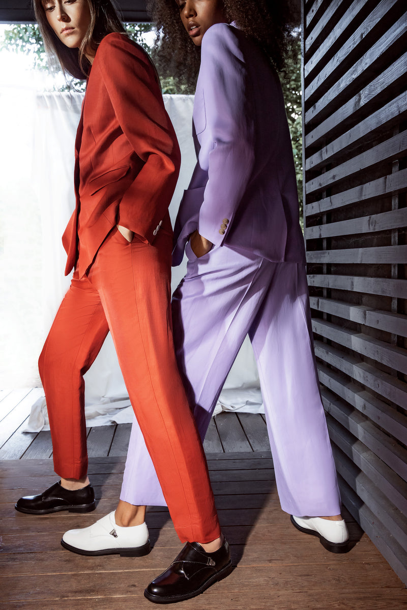 Woman in orange suit wearing CWEN black glossed monk shoes and woman in lavender colour suit wearing Off white glossed leather CWEN shoes